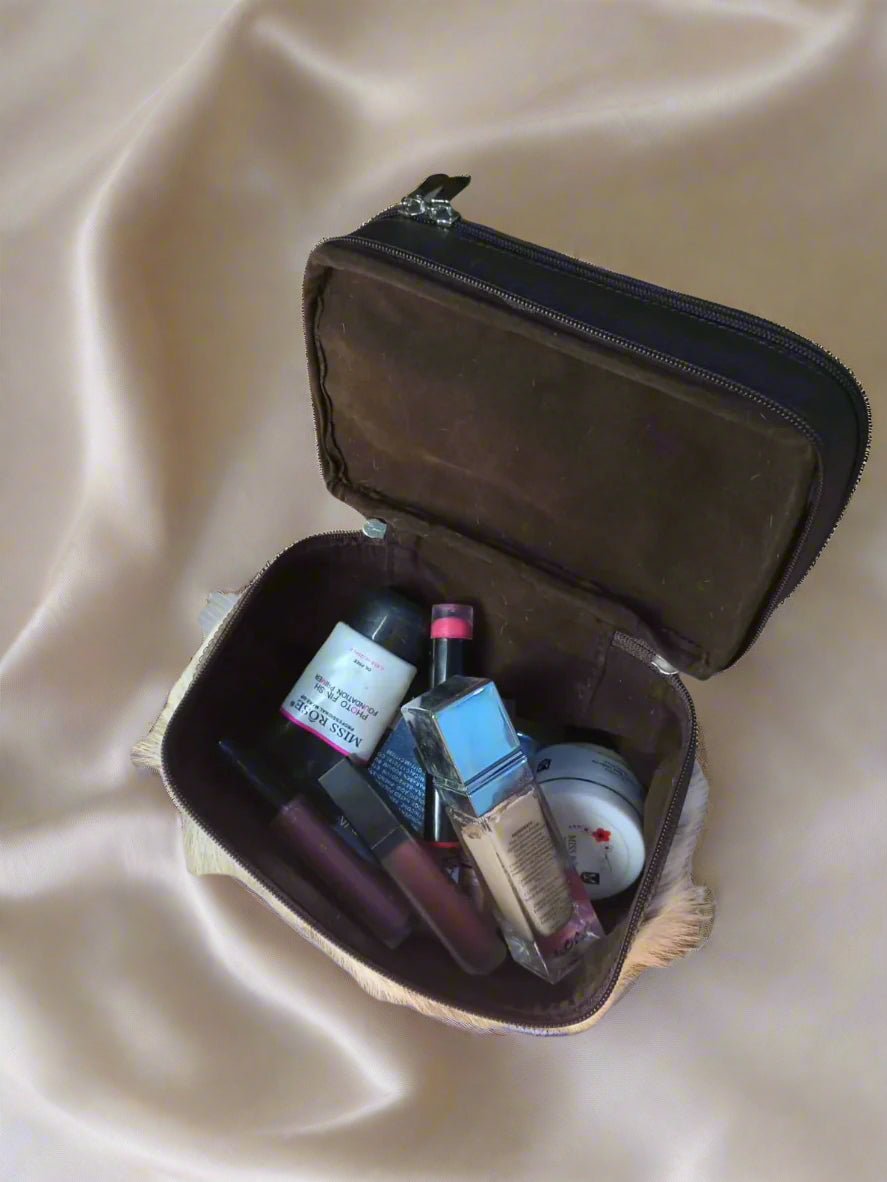 Open brown makeup case with cosmetic items on a wooden surface