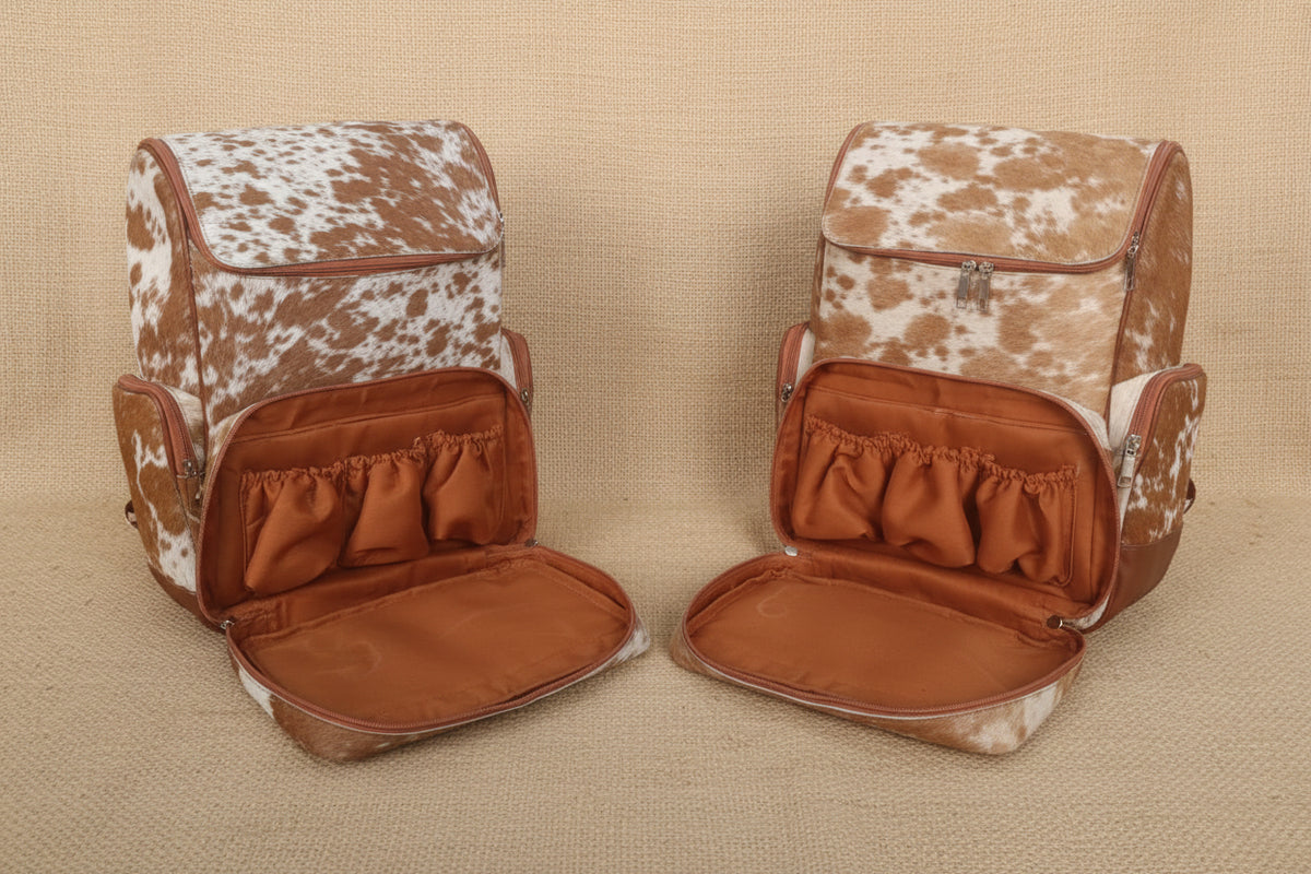 cowhide diaper backpacks placed on a beige jtefabric