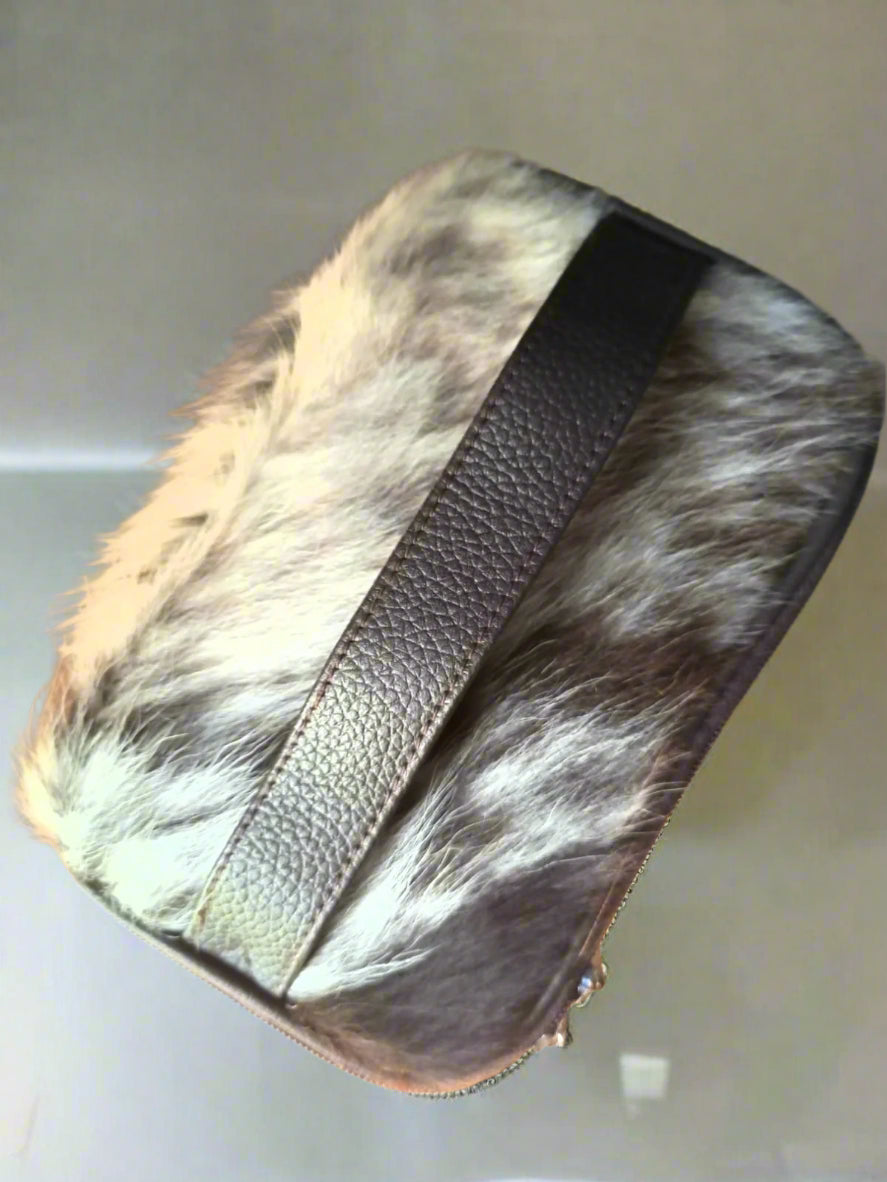 Fur leather makeup pouch with a leather strap on a clear surface