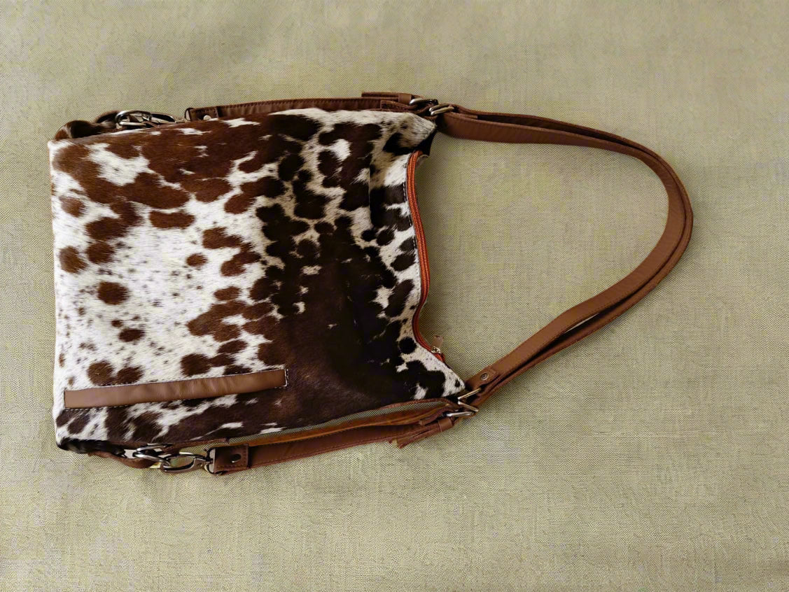 Brown and white cow print handbag on a beige background